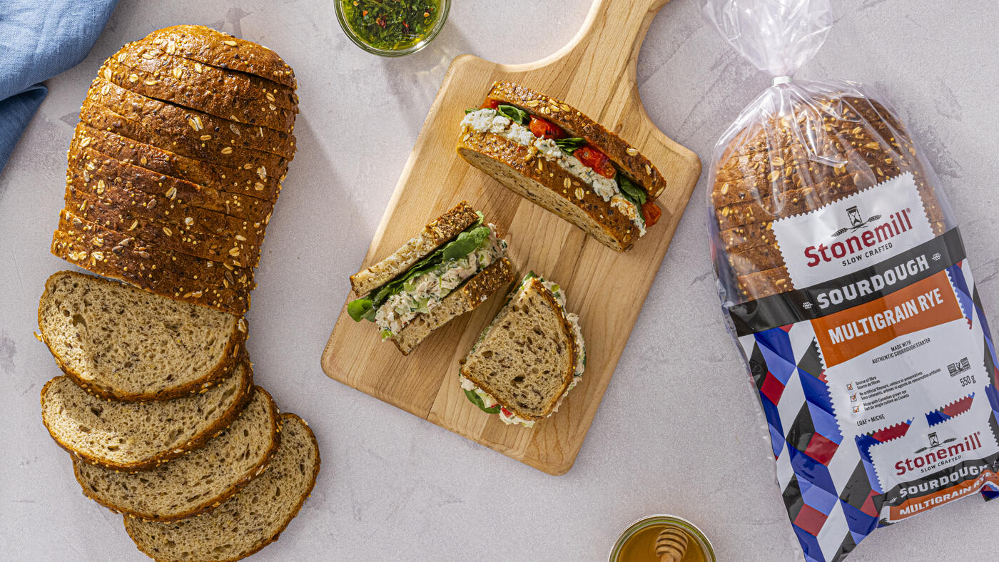 Product Hero - Sandwiches atop a cutting board with a loaf and a package of Stonemill Bread on either side